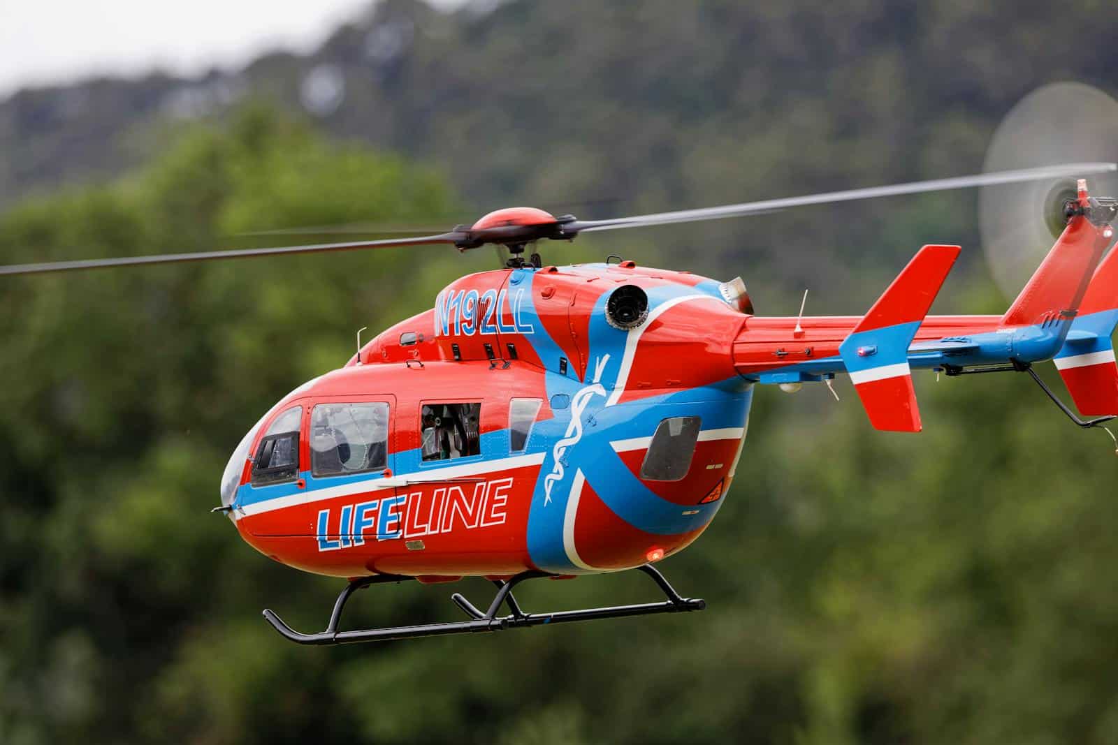 Close-up of a Lifeline helicopter in flight, showcasing its bold red and blue design.