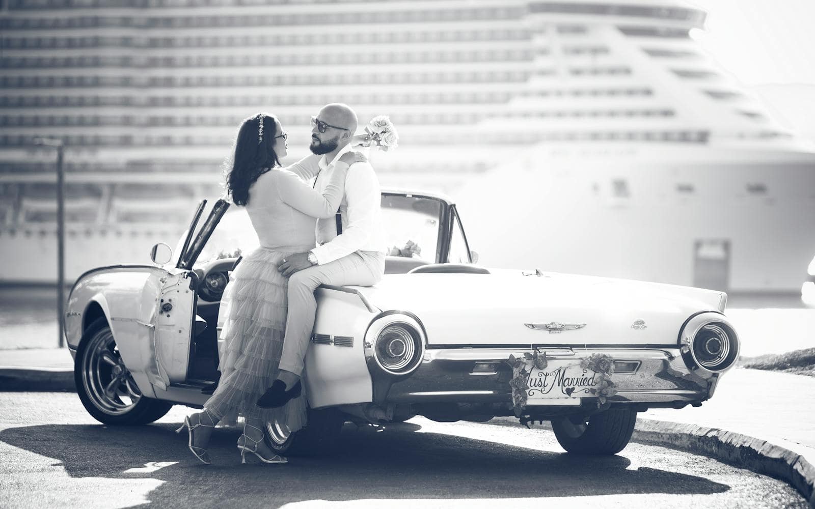 A joyful cruise wedding couple celebrating their marriage next to a classic car in scenic Puerto Plata.